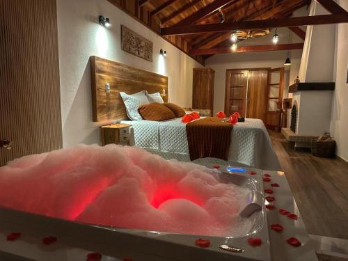 a bathroom with a bath tub with a bed in the background at Monte Verde Lofts Araucária in Monte Verde