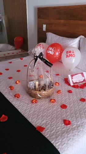 a bed with a basket of flowers and balloons at Monte Verde Lofts Araucária in Monte Verde