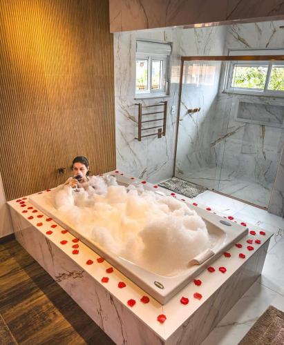 a man taking a picture in a bath tub at Monte Verde Lofts Araucária in Monte Verde
