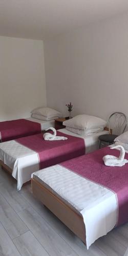 a room with three beds with white and purple sheets at Ночлеги - HOSTEL in Tarnowo Podgórne