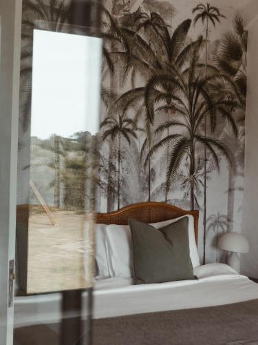 a bedroom with a bed with palm trees on the wall at Stanley Island in Plettenberg Bay