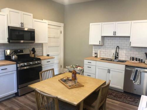 a kitchen with white cabinets and a wooden table with chairs at Eco Friendly Home by Cincy w Office Space in Dayton