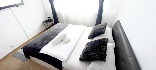 una cama blanca con almohadas en una habitación en COQUETTE 2-Dormitoare, en Baia Mare
