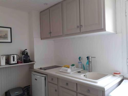 une cuisine avec des armoires blanches et un évier dans l'établissement Au bord du ciel Magnifique appartement à Bandol, à Bandol