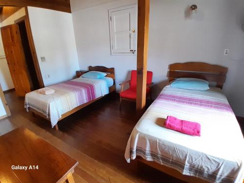 a bedroom with two beds and a red chair at Hostal Hansi in Bocas del Toro
