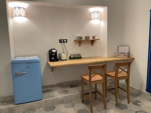 a kitchen with a counter with two chairs and a blue refrigerator at Le Gatte Rosa B&B in Bevagna