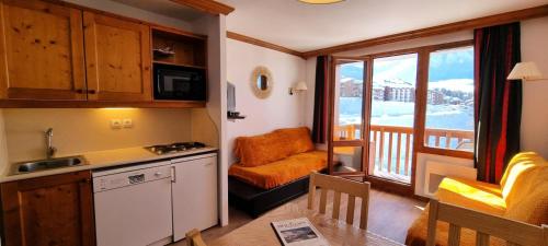 Il comprend une cuisine avec un balcon doté d'une chaise et d'une table. dans l'établissement Résidence Mont Soleil A - Appartement 5 personnes - Plagne Soleil MAE-0294, à Aime La Plagne