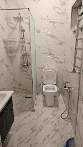 a white bathroom with a toilet and a shower at New Milan Mountain Ponoramic Hotel, with indoor heated swimming pool in Gabala