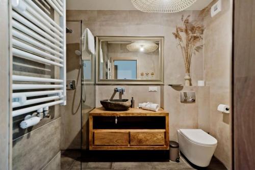 Un baño con lavabo, inodoro y espejo. en Angel Apartment in Porto Łeba, en Łeba