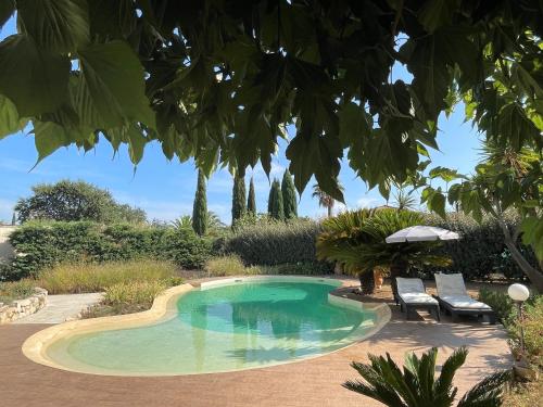 a swimming pool with two chairs and an umbrella at Le Vieux Murier - Chambres d'hôte in Hyères