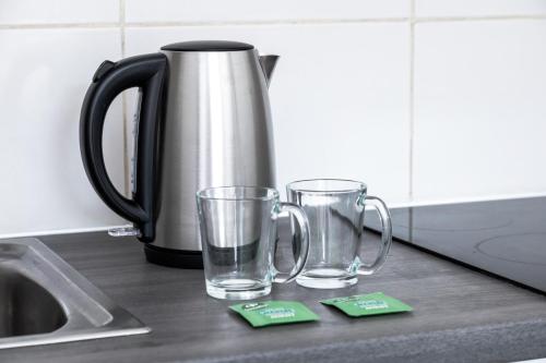 deux verres vides assis sur un comptoir à côté d'une cafetière dans l'établissement Appartement F1 proche de Disney, à Chaumes-en-Brie