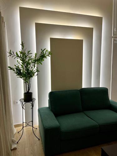 a green couch in a living room with a plant at Emerald Luxury Apartments - ATH Airport in Spáta