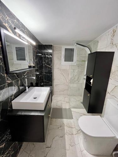 a bathroom with a white sink and a toilet at Emerald Luxury Apartments - ATH Airport in Spáta