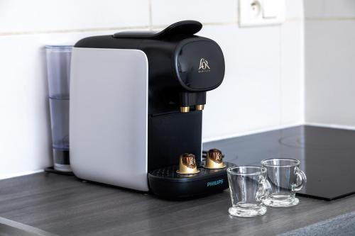 - une cafetière sur un comptoir avec deux verres dans l'établissement Appartement F1 proche de Disney, à Chaumes-en-Brie