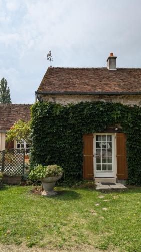 Cette maison recouverte de lierre dispose d'une porte et d'une fenêtre. dans l'établissement Pause de bonheur à la campagne, à Mareau-aux-Bois