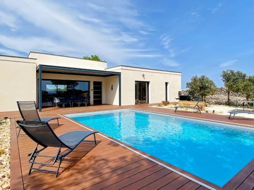 une piscine avec deux chaises et une maison dans l'établissement Villa moderne piscine privative hauteurs de Nimes, à Nîmes