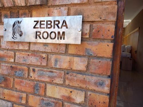 a sign that reads zebra room on a brick wall at Inni Bush Guesthouse in Noordheuwel