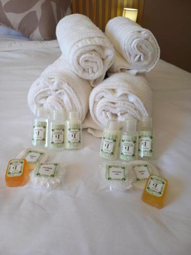 a pile of towels on a bed with bottles of soap at Inni Bush Guesthouse in Noordheuwel