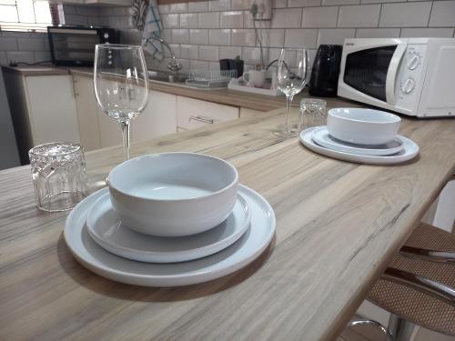 a table with two bowls and plates and wine glasses at Inni Bush Guesthouse in Noordheuwel
