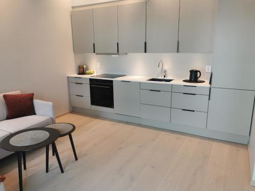 a kitchen with white cabinets and a couch and a table at Svolvær city center, harbour apartment in Svolvær