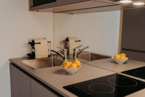 a kitchen with a sink and two bowls of oranges at An der Lage - Exklusives Apartment mit Toskana Flair in Obegg