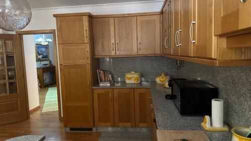 a kitchen with wooden cabinets and a black microwave at Appartement tout confort Valpaços 2 in Valpaços