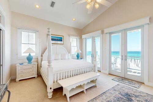 a bedroom with a white bed and a balcony with the ocean at Deja Vu at Carillon in Carillon Beach