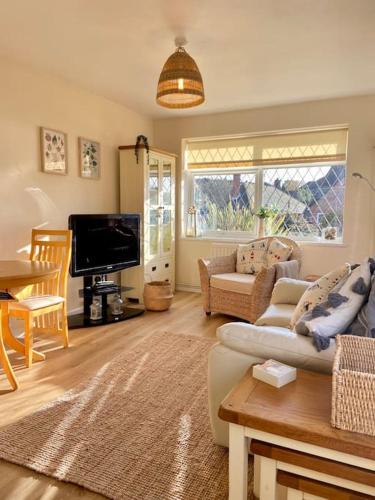 a living room with a couch and a tv at Spacious bungalow Air con & Wi-fi in Sidley