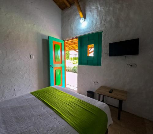 a bedroom with a bed and a green door at Hotel Parque de los Arrieros in Montenegro