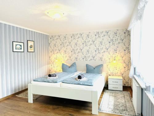ein Schlafzimmer mit einem weißen Bett mit blauen Kissen in der Unterkunft F-1112 Ferienwohnung Lobbe Haus strandnah, Terrasse in Lobbe