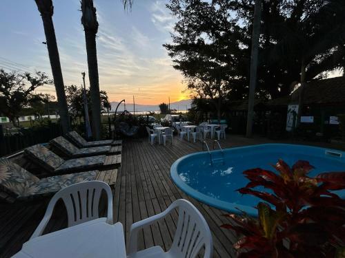 a hot tub on a deck with chairs and tables at Pousada Canoa Azul na Praia da Ferrugem in Garopaba