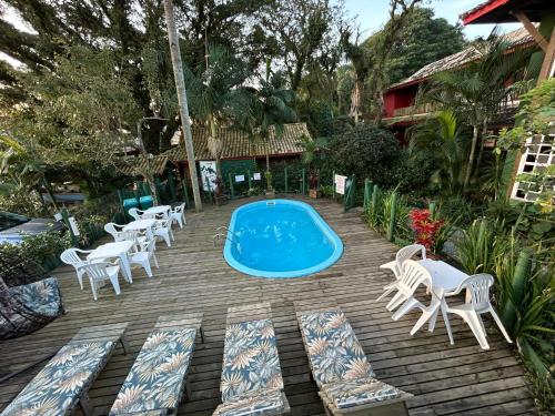 a patio with chairs and a pool and a bunch ofitures at Pousada Canoa Azul na Praia da Ferrugem in Garopaba