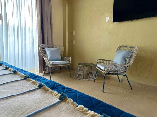 a room with two chairs and a table and a television at Lolitas Suites 304 in Zihuatanejo