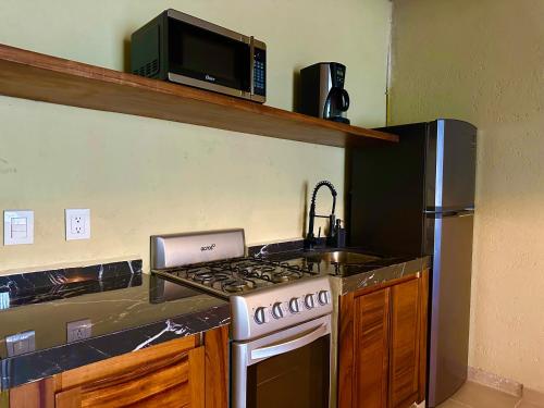 a kitchen with a stove and a microwave at Lolitas Suites 304 in Zihuatanejo