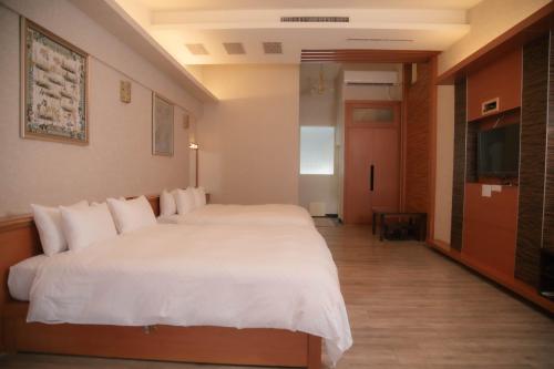 a hotel room with a white bed and a television at Guanziling Lin Kuei Yuan Hot Spring Resort in Baihe