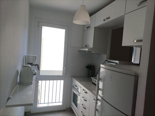 Il comprend une cuisine avec une fenêtre et un réfrigérateur blanc. dans l'établissement Agréable Appartement Proche Plage - Linge de lit et Toilettes en option, à La Grande Motte