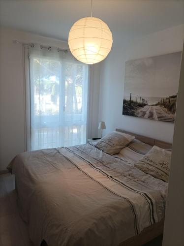 une chambre avec un grand lit avec une grande fenêtre dans l'établissement Agréable Appartement Proche Plage - Linge de lit et Toilettes en option, à La Grande Motte