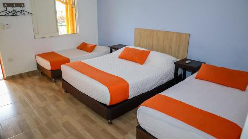 a room with two beds with orange and white at Hotel Parque de los Arrieros in Montenegro