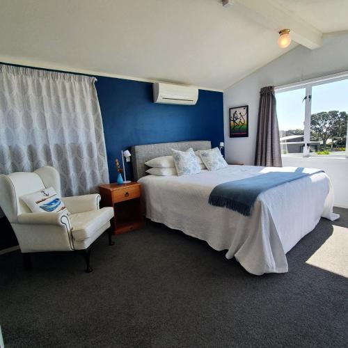 a bedroom with a large bed and a chair at Oneroa Bay View Apartment in Oneroa