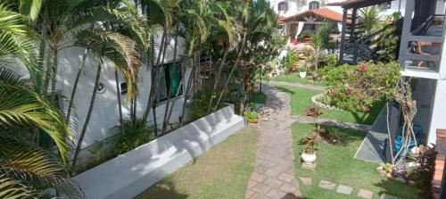 a garden with palm trees and a building at Atlântico Hotel in Rio das Ostras