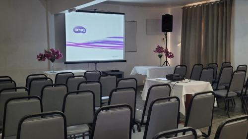a conference room with tables and chairs and a screen at Atlântico Hotel in Rio das Ostras