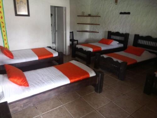 a room with three beds with orange and white sheets at Hotel Parque de los Arrieros in Montenegro