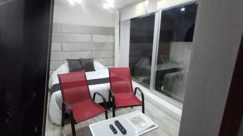 two red chairs and a bed in a room at Mirador samsara Suite vista al bosque 25 mt2 in La Calera
