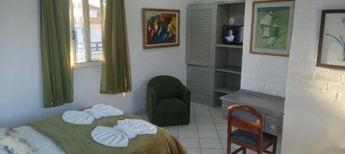 a bedroom with a bed with a chair and a desk at Atlântico Hotel in Rio das Ostras