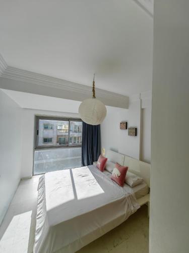 a white bedroom with a large bed with red pillows at City Bleu Maroc in Tangier