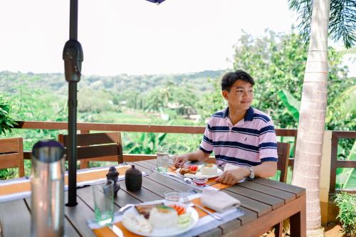 a man sitting at a table with a plate of food at Casa de Simone BAGAC in Bagac