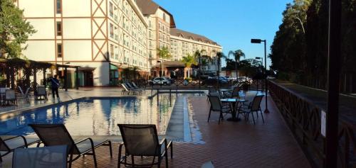 a pool with chairs and a table in front of a building at Condomínio Vista Azul Hotel in Pedra Azul