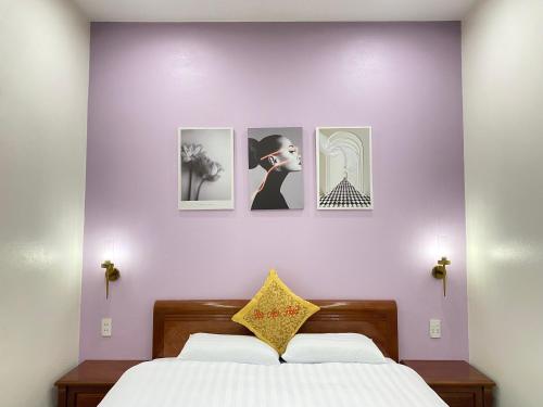 a bedroom with four pictures on a purple wall at Van Anh Hotel - Restaurant in Dồng Văn