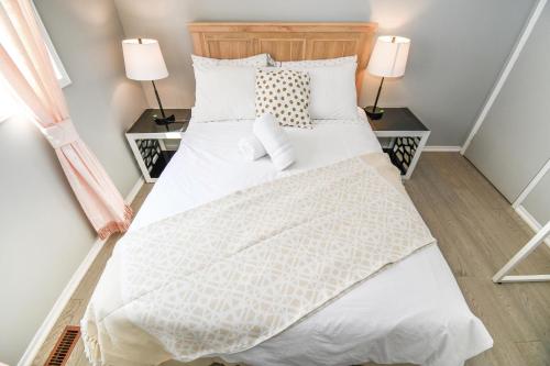 a bedroom with a bed with white bedding and two lamps at Lake Simcoe 4 Bedroom Family Home Ideal Toronto Area Retreat in Innisfil