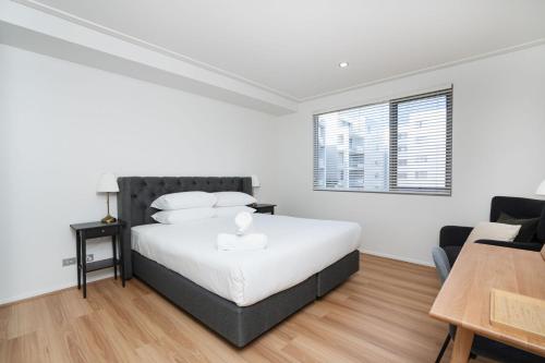 a white bedroom with a bed and a window at Modern 1-Bed Unit with Pool Views and Balcony in Canberra